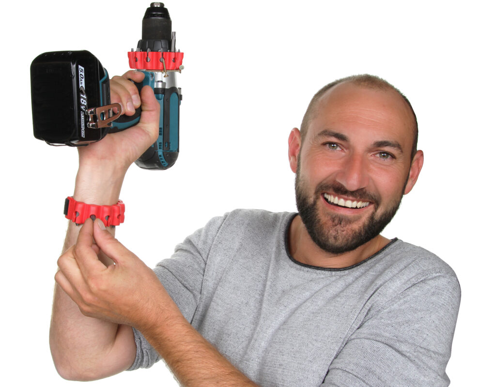 Fabien Escherich souriant, inventeur du bitpass avec un bitpass au poignet et un sur une perceuse